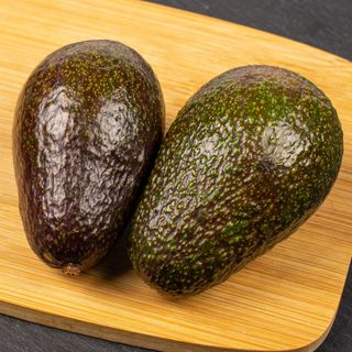 Two avocados on chopping board
