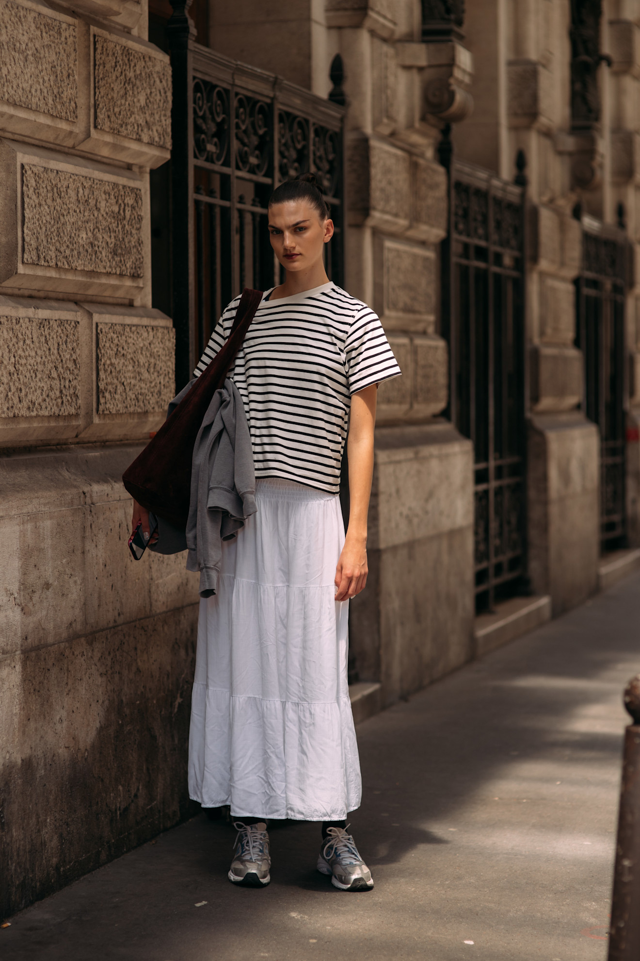a fashion week attendee wears a striped t-shirt, white skirt, and sneakers
