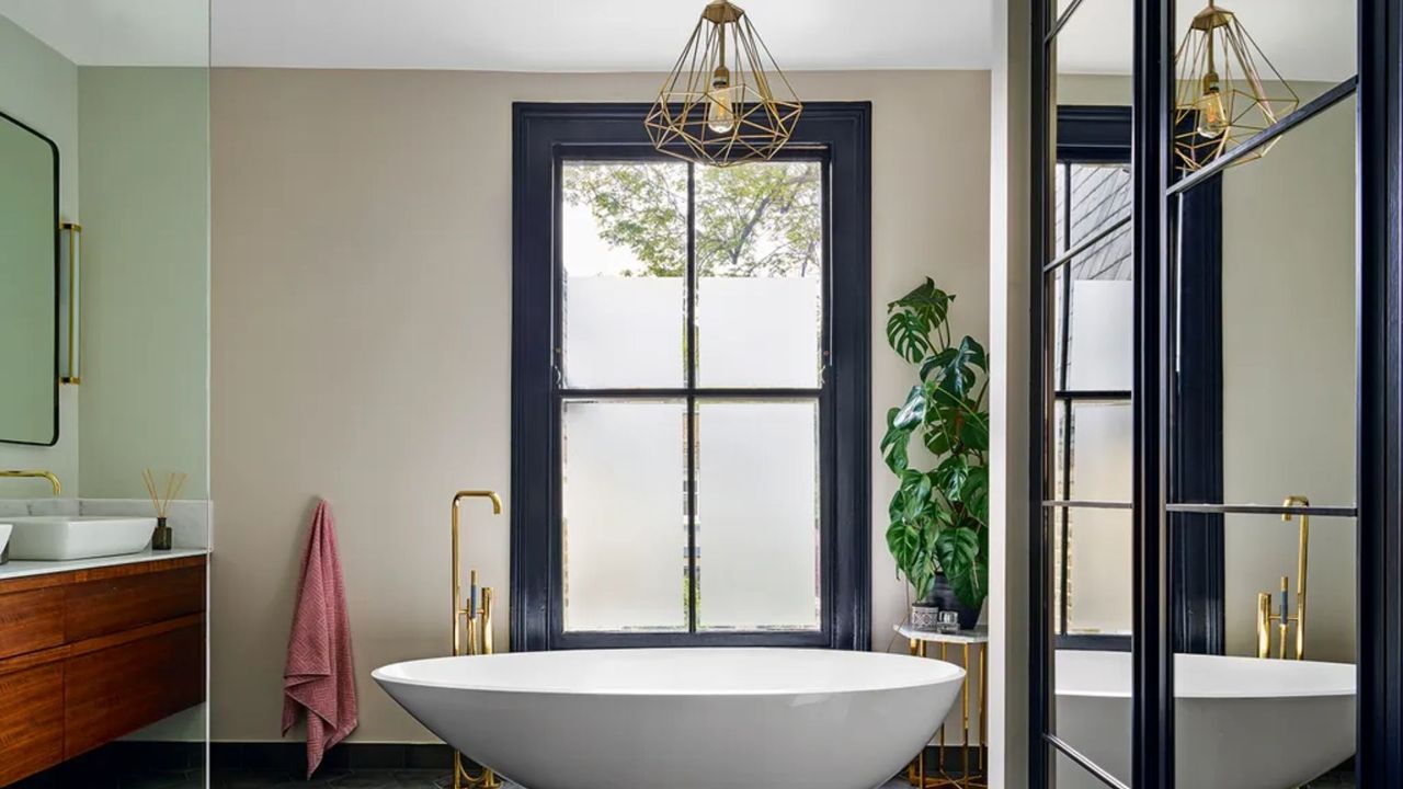 large bathroom with freestanding bath tub and monstera plant and green walls