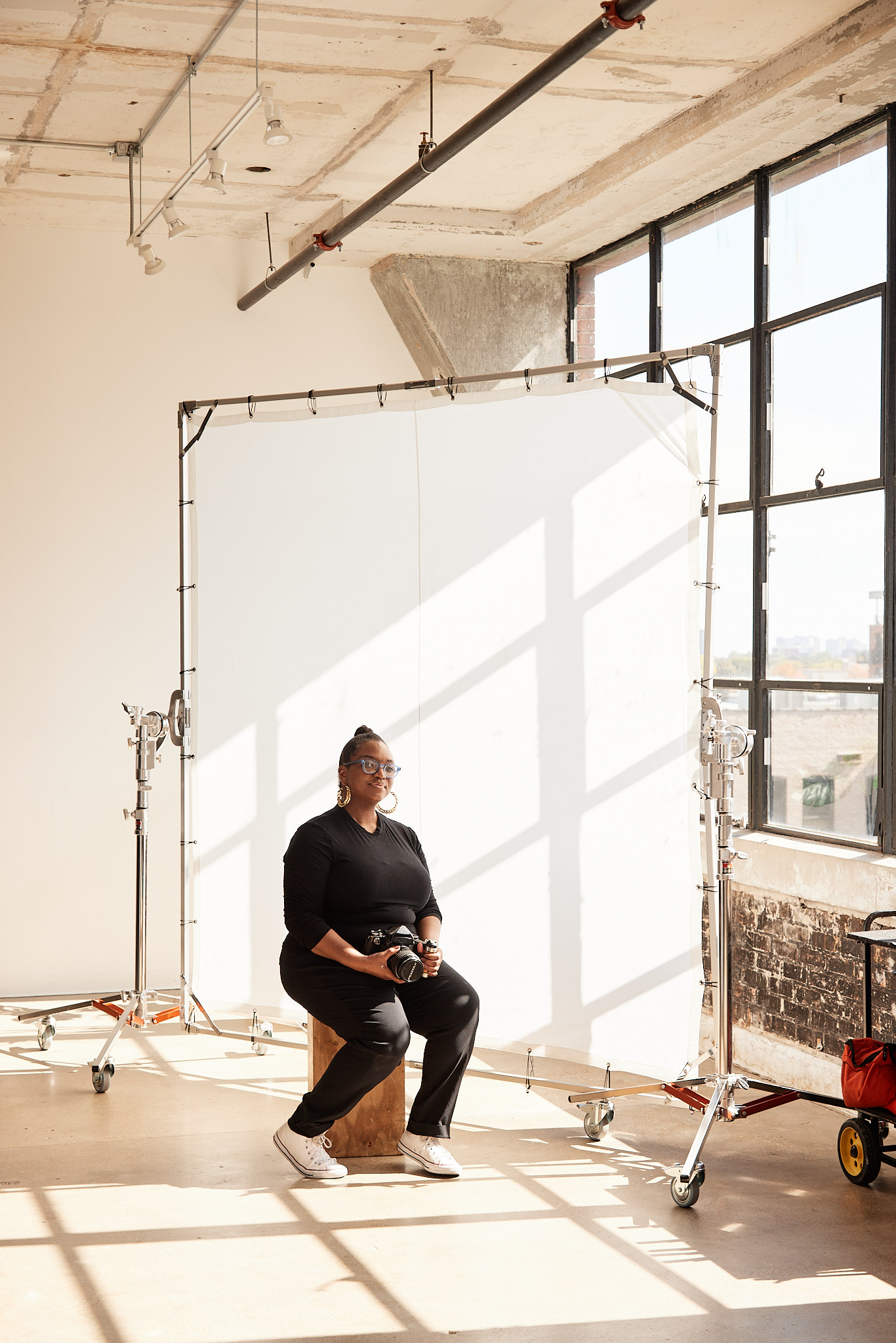 black women directors founder danielle scruggs poses holding a camera in a well lit photo studio
