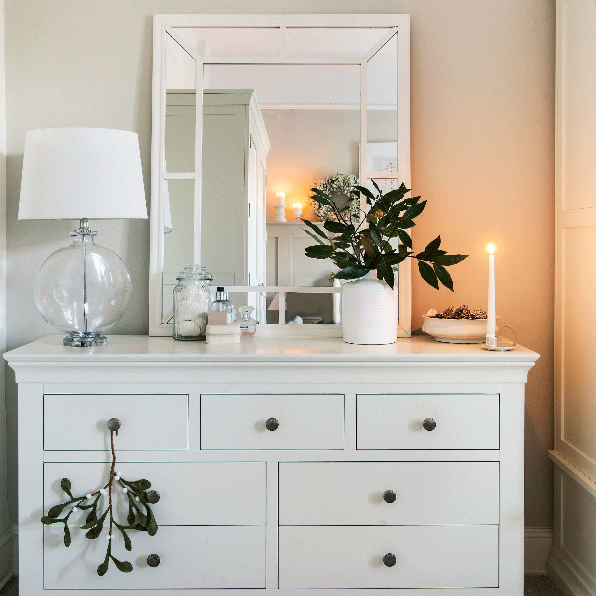 a cream chest of drawers with a mstching mirror and glass table lamp
