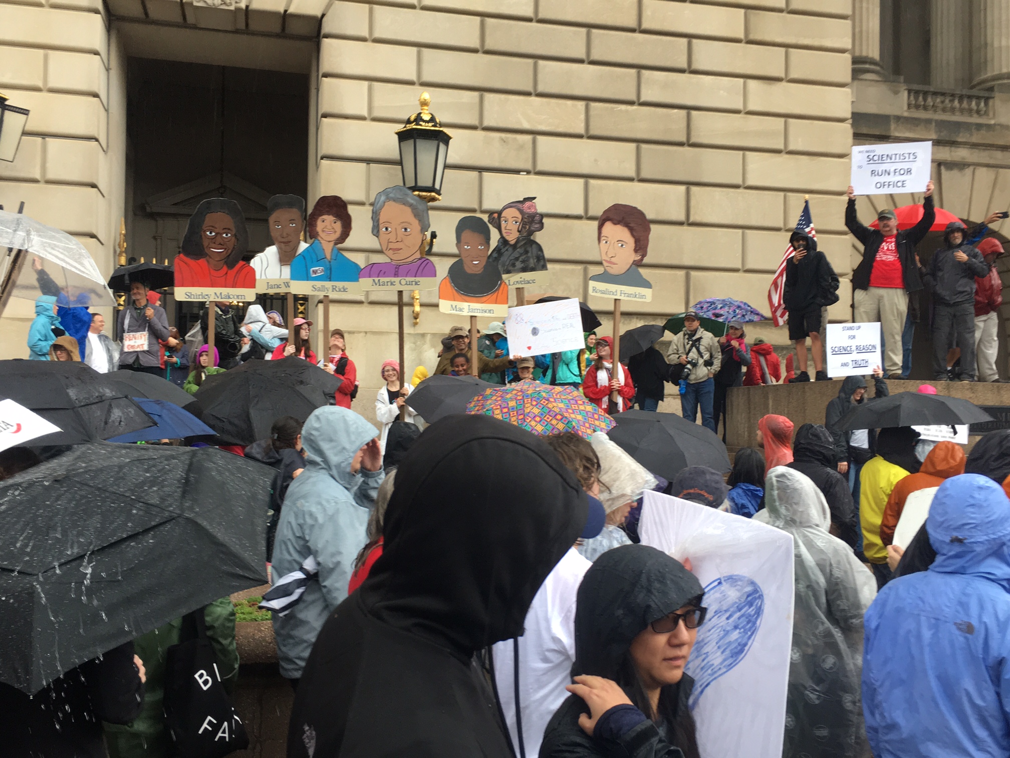 Marchers celebrate pioneering female scientists while standing in front of the Andrew W. Mellon Auditorium in Washington, D.C.