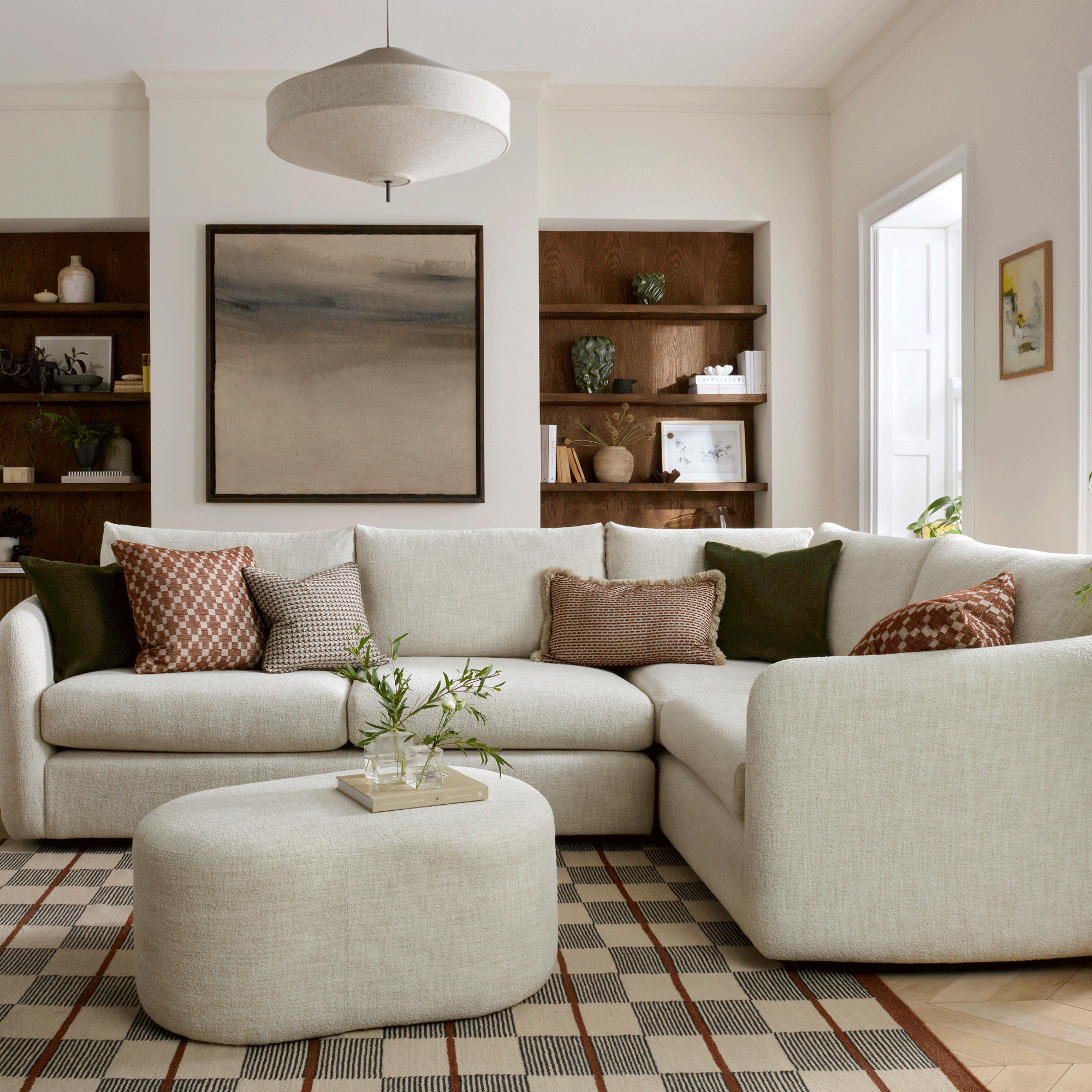 a cream sofa with matching footstool in a neutral living room