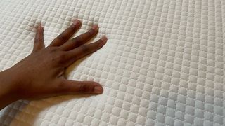 Our reviewer places her hand on top of the Simba Hybrid Mattress to see how cool to the touch it is