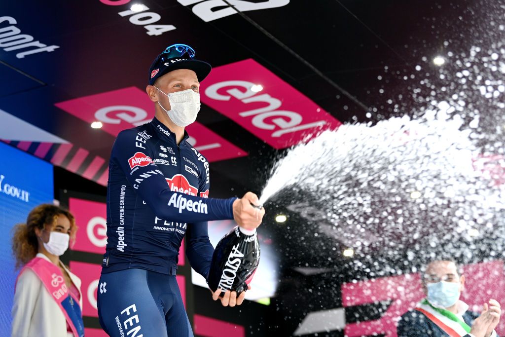 Tim Merlier (Alpecin-Fenix) celebrates his stage victory on the podium in Novara