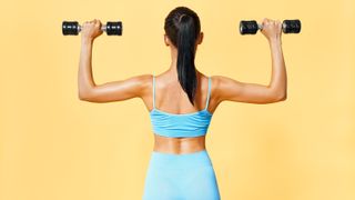 a woman in a blue workout set lifting two light dumbbells