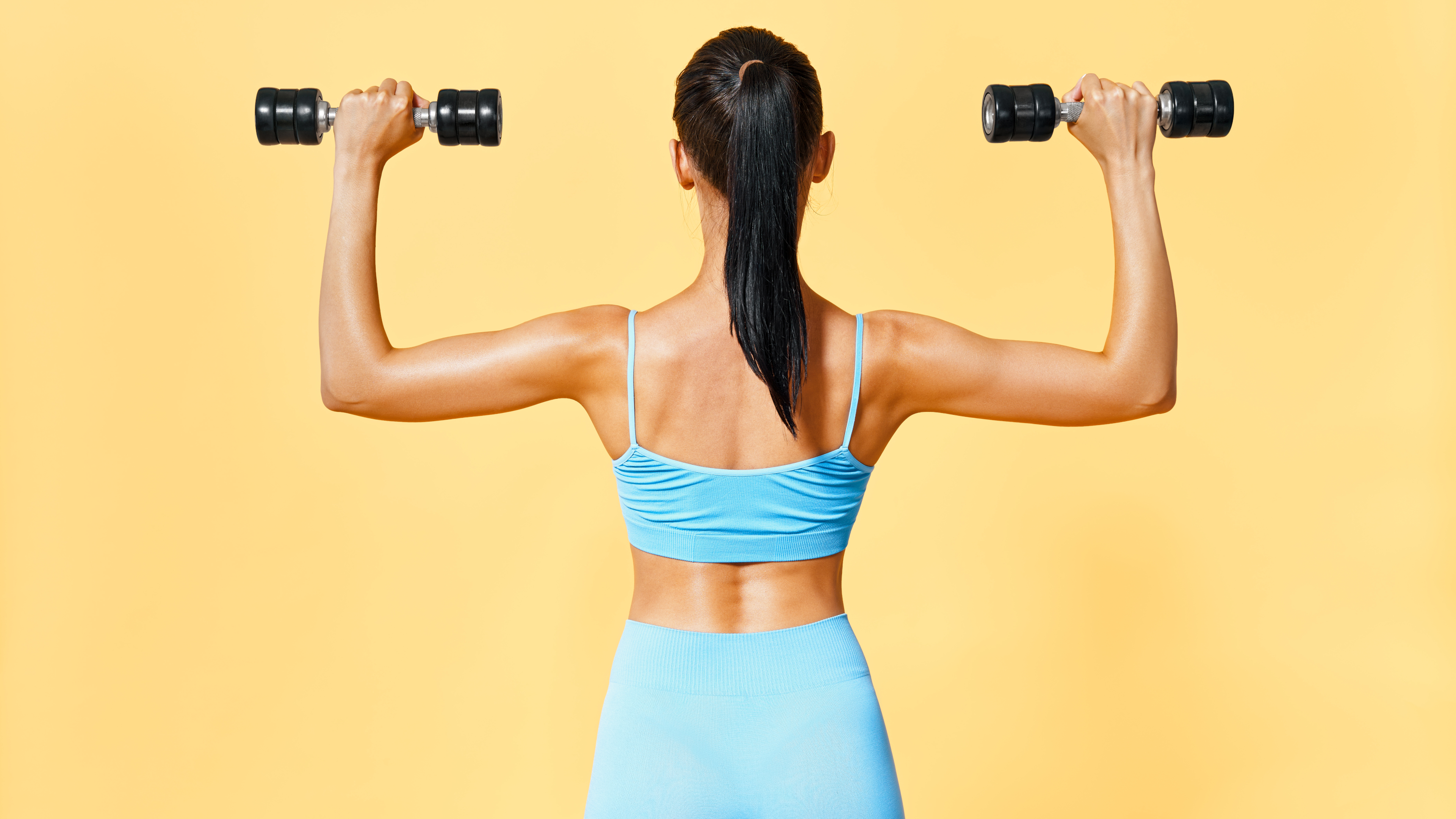 a woman in a blue workout set lifting two light dumbbells
