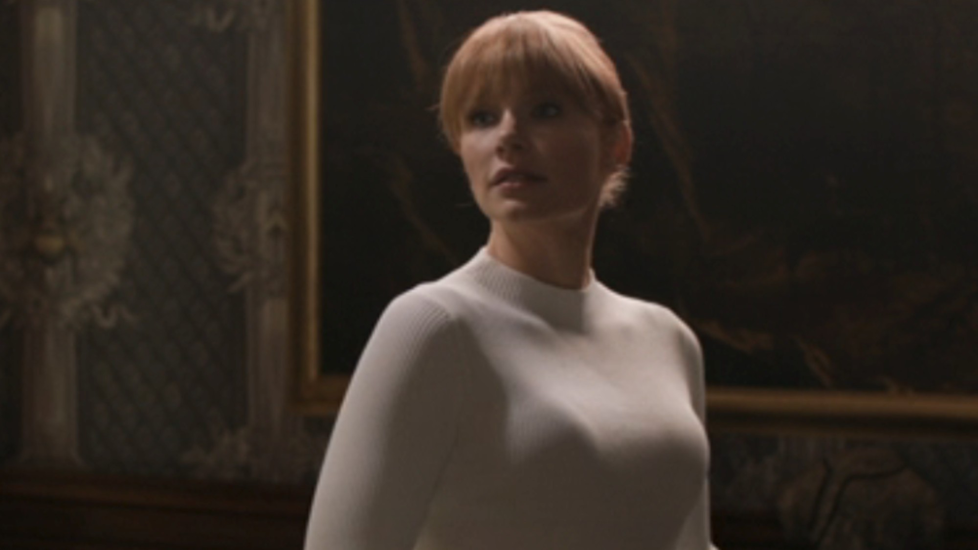 Bryce Dallas Howard in a white sweater with a dark background in a mansion in Jurassic World: Fallen Kingdom