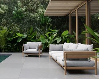 A teak wood outdoor sofa and armchair by a tropical pool