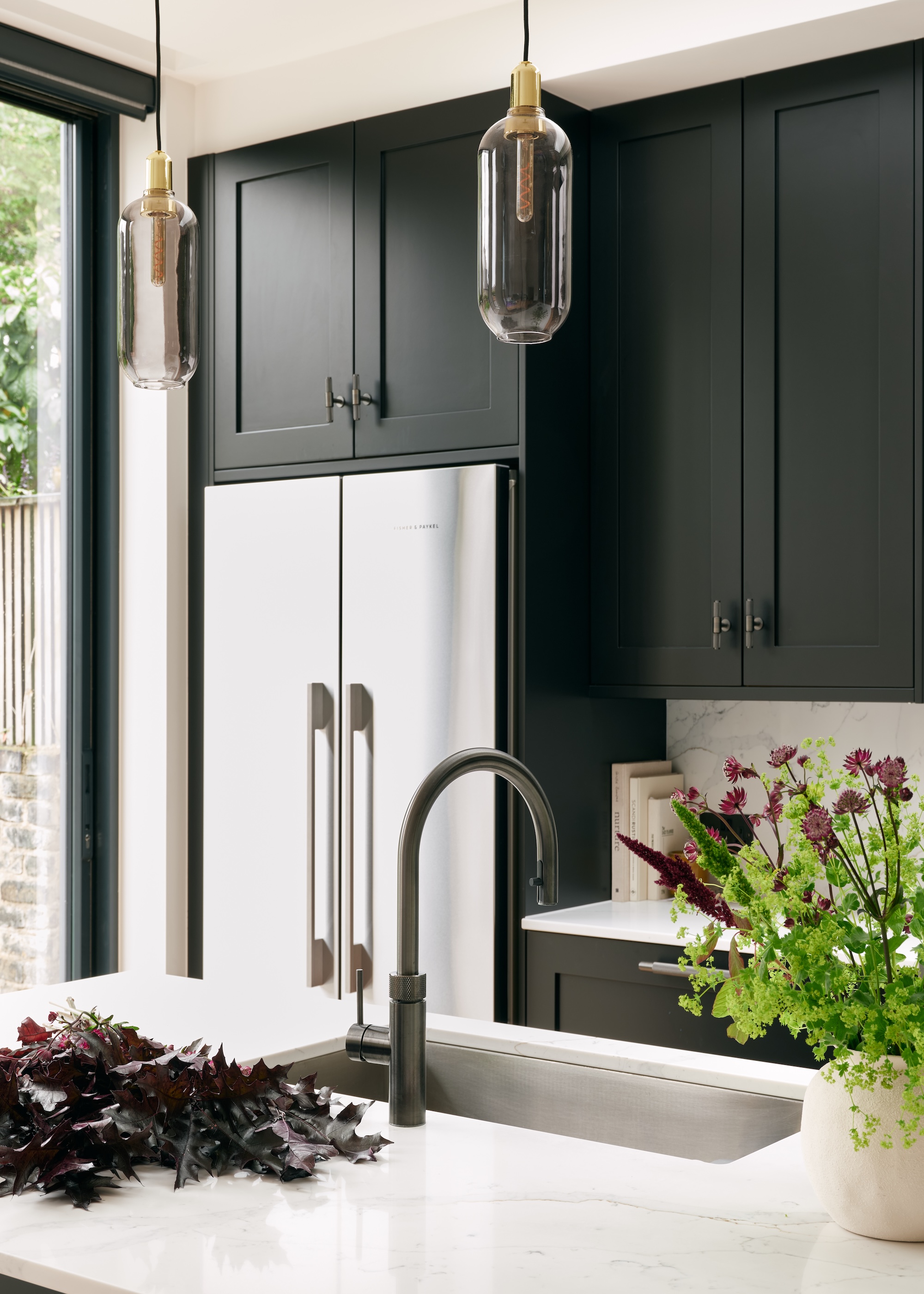 a gunmetal finish kitchen tap shown in a charcoal colored kitchen with sleek marble worktops