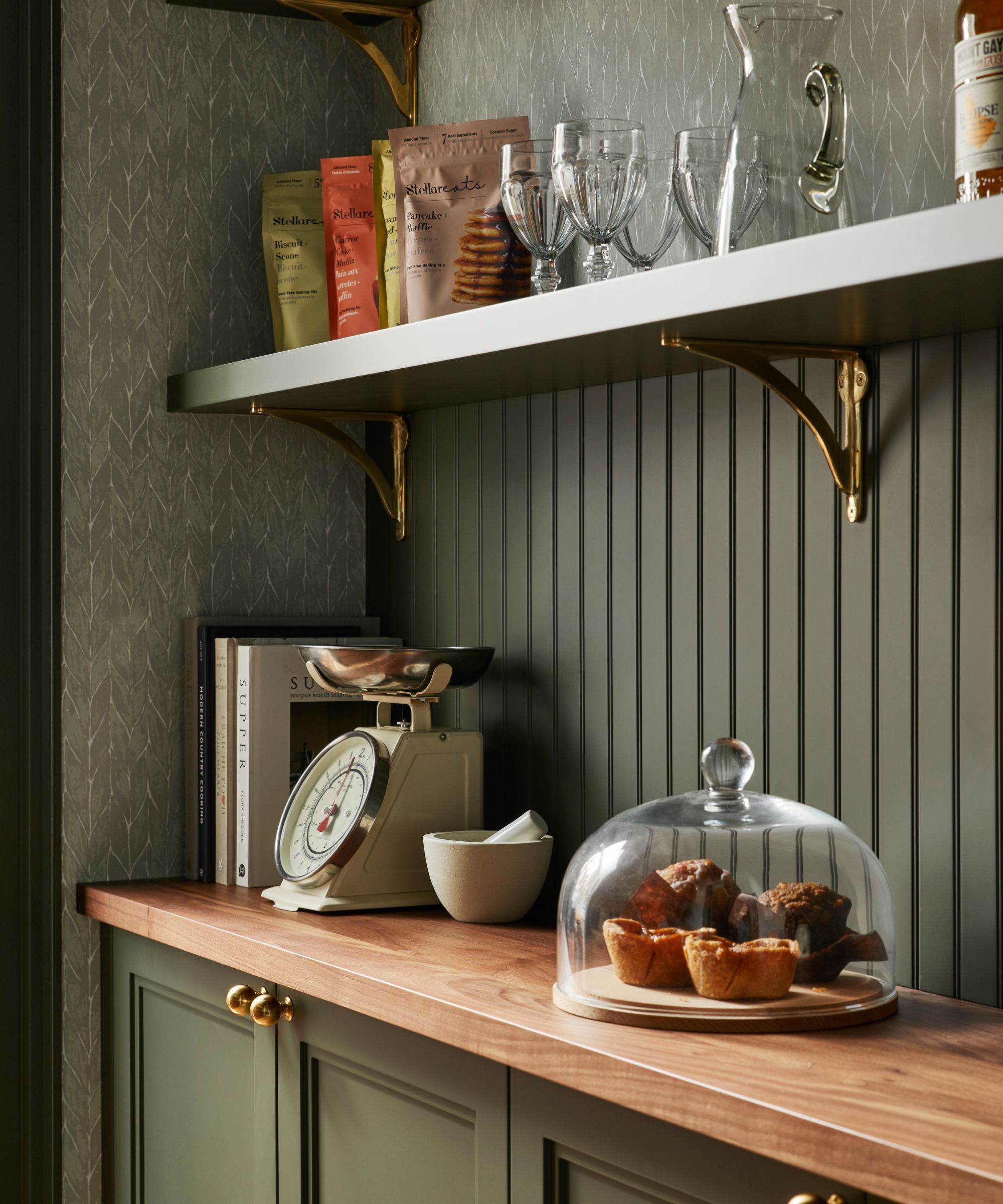 a mid green painted pantry with beadboard walls, wallpaper, and a wooden counter beneath open shelving