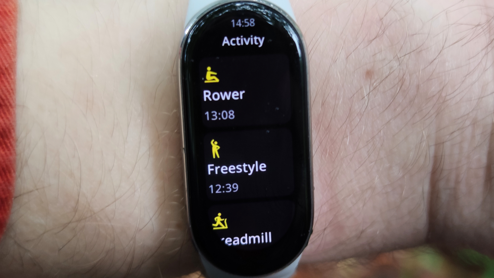 The Xiaomi Smart Band 9 on a man's wrist in front of a green park.