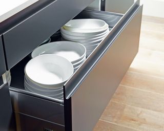 An open kitchen drawers storing white crockery