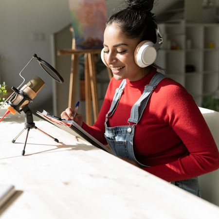 A young woman works on her side hustle podcast from home