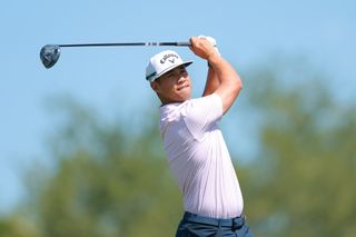 Isaiah Salinda watches a tee shot with a driver