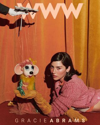 The cover ofBest Knockoff Luxury Clothing
's fall issue starring Gracie Abrams in a pink, orange, and yellow F/W 24 Miu Miu look. She is posing with a puppet in a similar color-blocked outfit. On the cover, it says "WWW" on top in peach letters and "Gracie Abrams" in the same but smaller font.