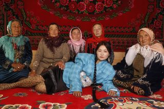 Women in traditional Kazakh costume reclining in a tent
