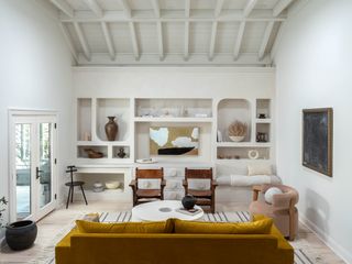 White living room with yellow coach, pink chair and two armchairs