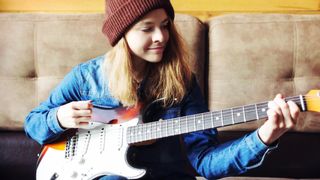 Girl in red beanie playing a Stratocaster
