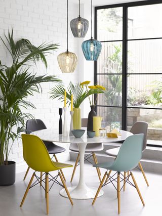 small white dining room with a round table and cluster pendants by Pooky
