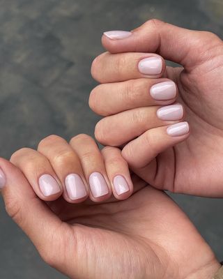 A woman wearing OPI's Love Is In The Bare nail polish