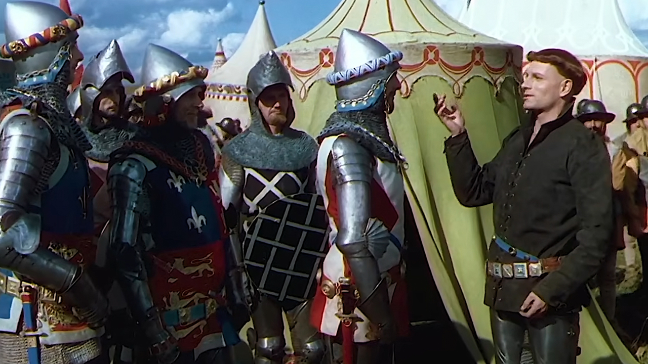 Laurence Olivier in traditional costume speaking to knights in Henry V.