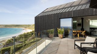 A self build on a cliffside with a sunny terrace clad in black timber