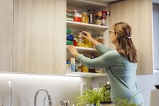 Woman picking an ingredient jar from cupboard kitchen 