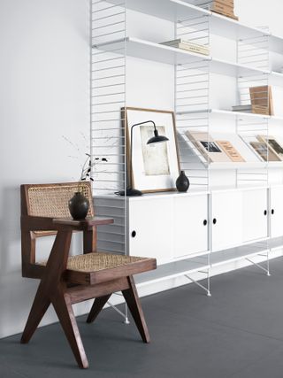 White shelving unit next to wicker chair