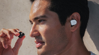 A man wearing the Master and Dynamic MW08 Sport earbuds in white