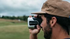 A golfer looking through a Precision Pro laser rangefinder