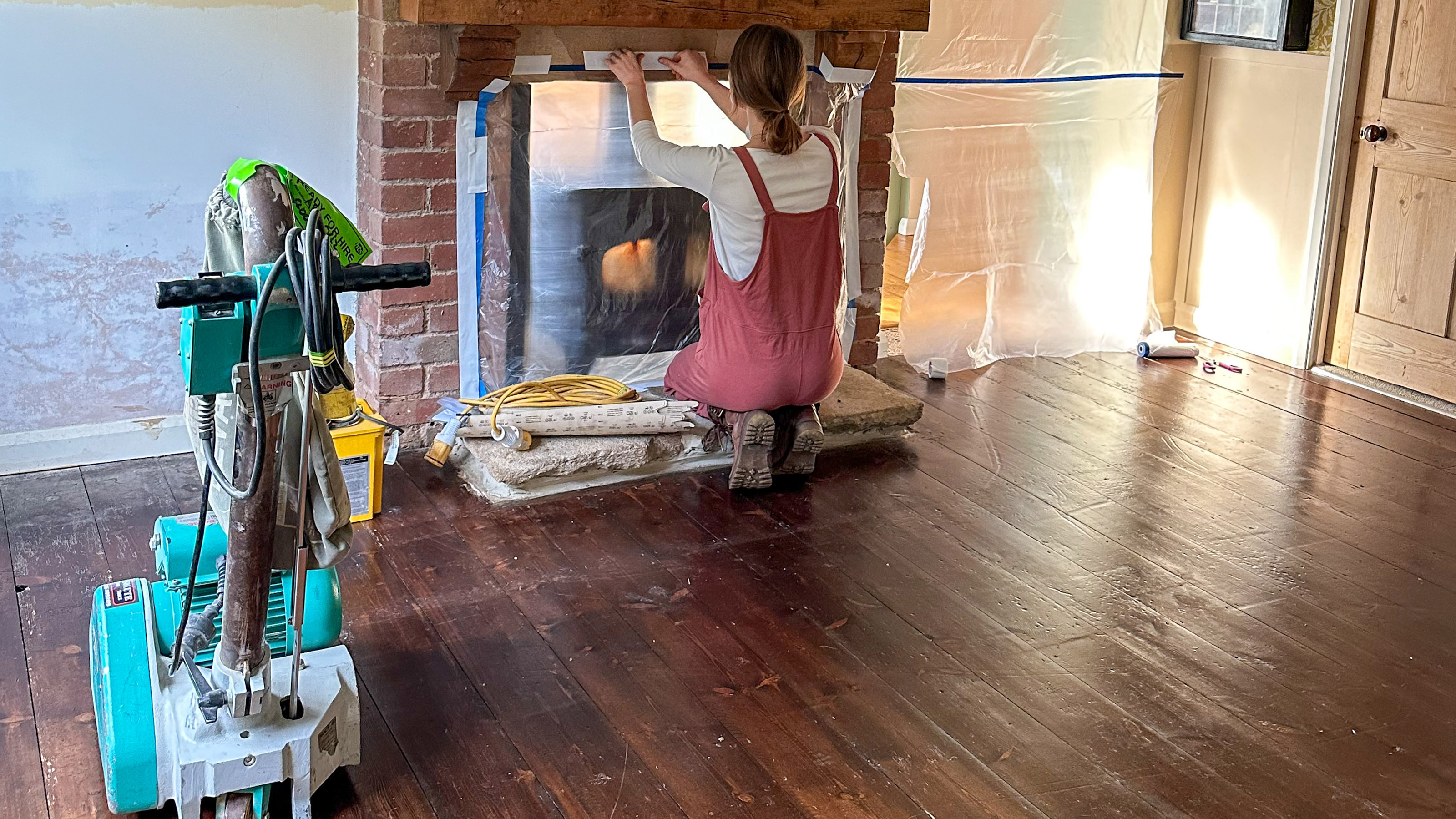 a woman partway through a diy project of sanding her wooden floor