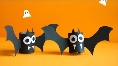 halloween craft ideas: bats made from toilet role tube on an orange background
