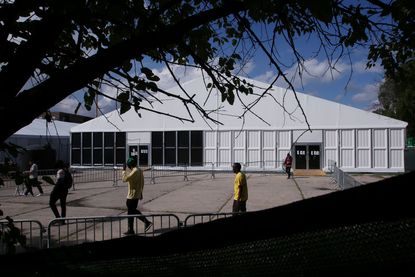 People are seen around the "tent city" for migrants at Creedmoor Psychiatric Center on August 16, 2023 in the Queens borough of New York City. The "tent city" meant for migrants opened on Tuesday and is expected to host about 1,000 migrants as state officials struggle to handle the influx of asylum seekers.
