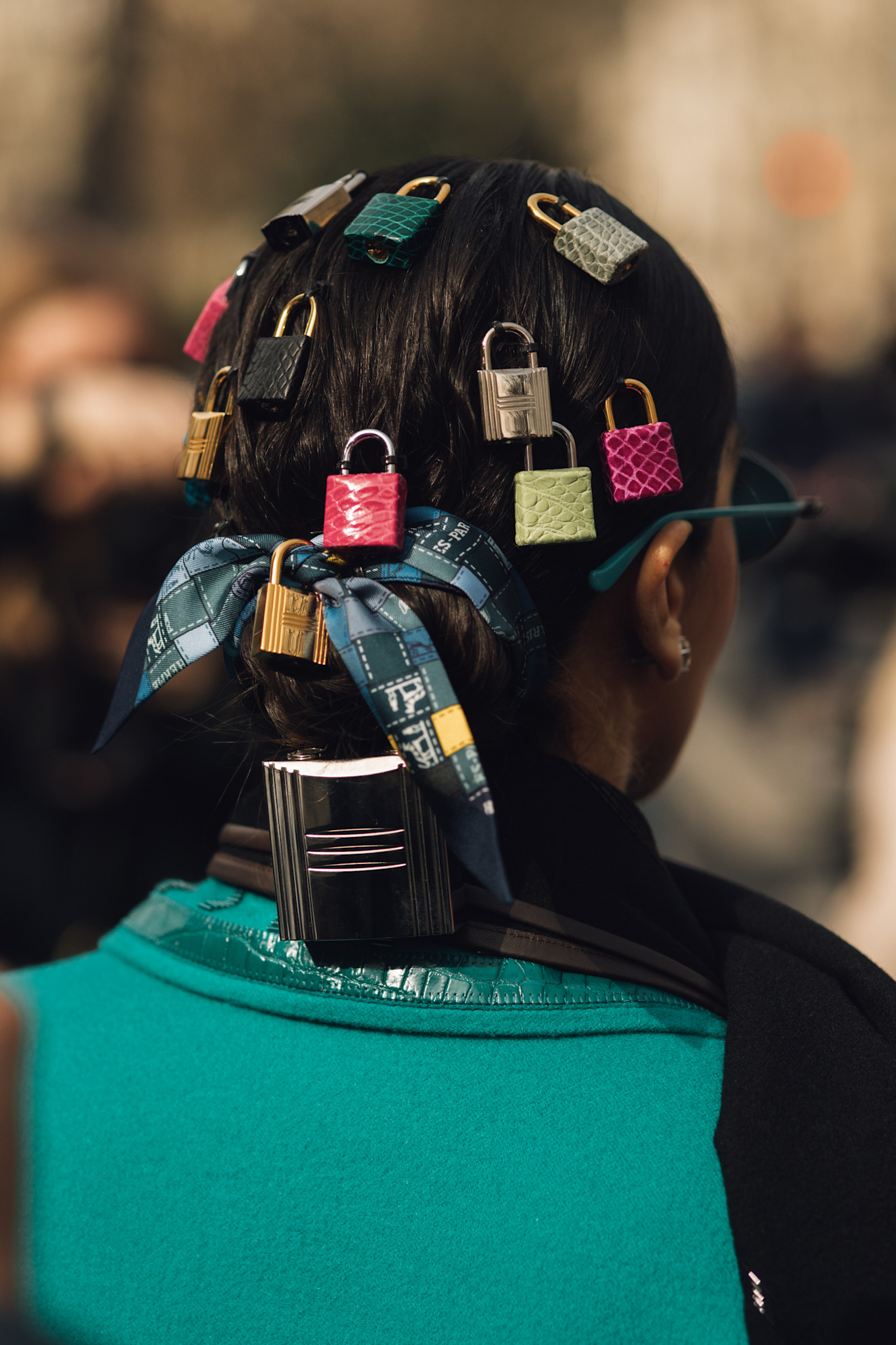 A photo of the back of a woman's hair at Paris Fashion Week AW26, which is adorned with padlocks, ribbons and a ponytail cuff