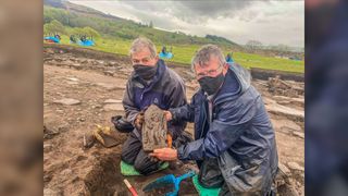 Volunteer excavators Richie Milor and David Goldwater hold the carved stone they found at Vindolanda.