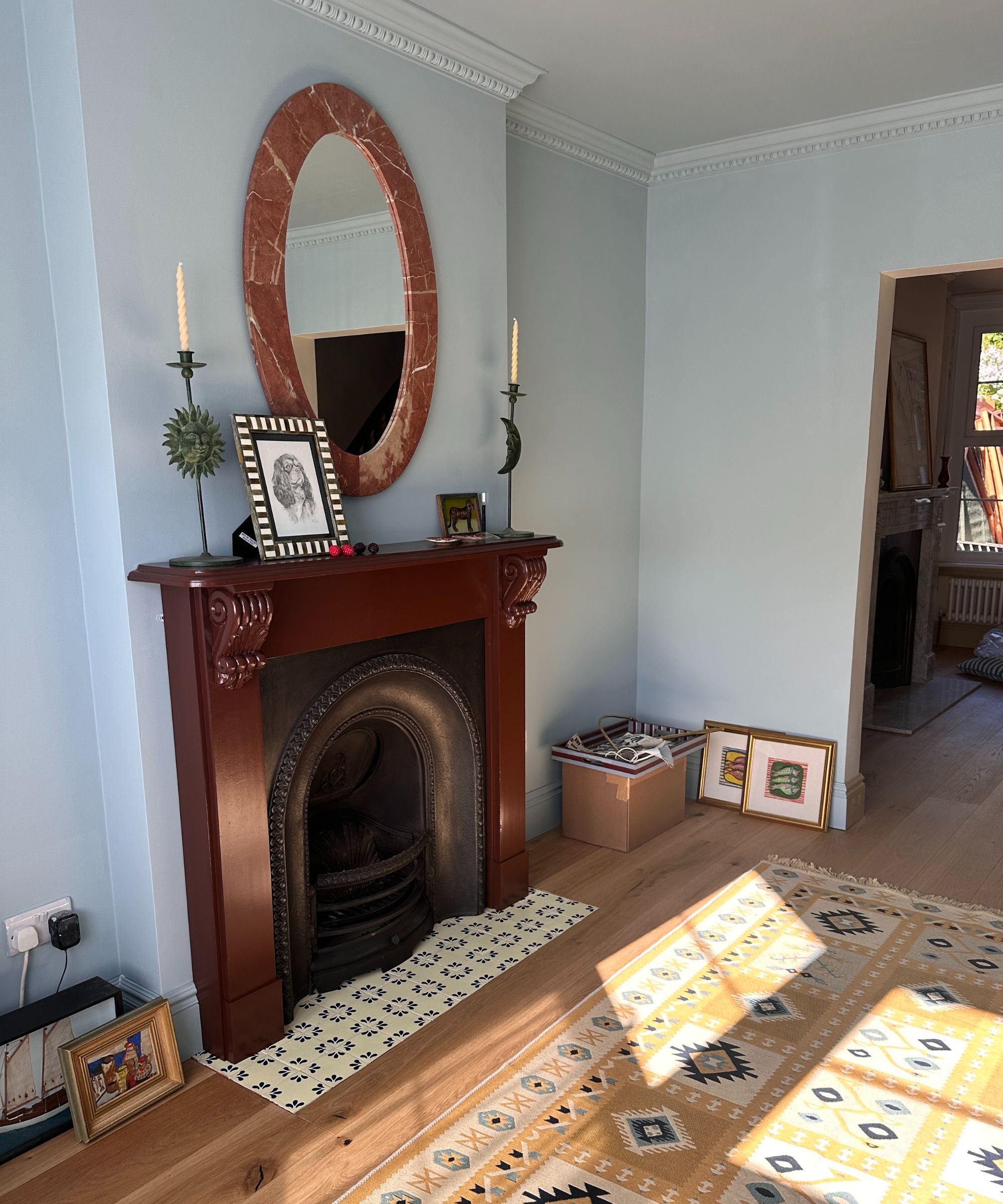 blue color drenched living room with a chocolate brown painted fireplace with blue and white hearth tiles and a yellow rug