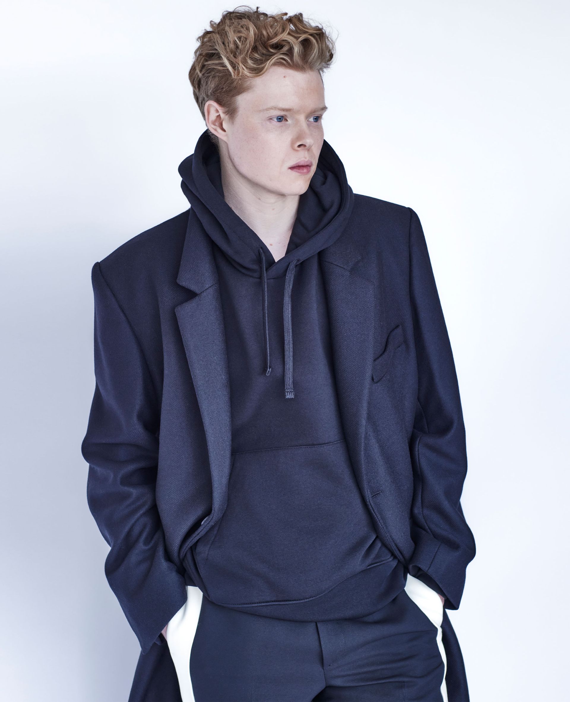Kai Alexander wearing a navy hoodie styled with a matching blazer and pants.