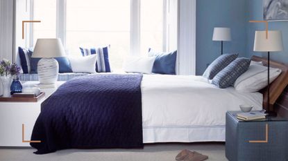 Blue bedroom with a bed with crisp white bedding and a navy blue throw draped across the end of the bed