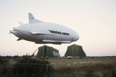 The Airlander blimp hovers over airship sheds in Bedfordshire