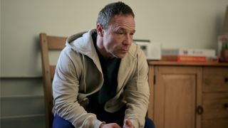 Andy (Stephen Graham) sitting on a wooden chair in a cream hoodie in Boiling Point episode 4