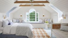 Eastcoastal bedroom featuring a cream-and-white diamond pattern jute area rug, patterned bedding, a high thatched ceiling with exposed wood planks, and a window daybed on the far side of the room