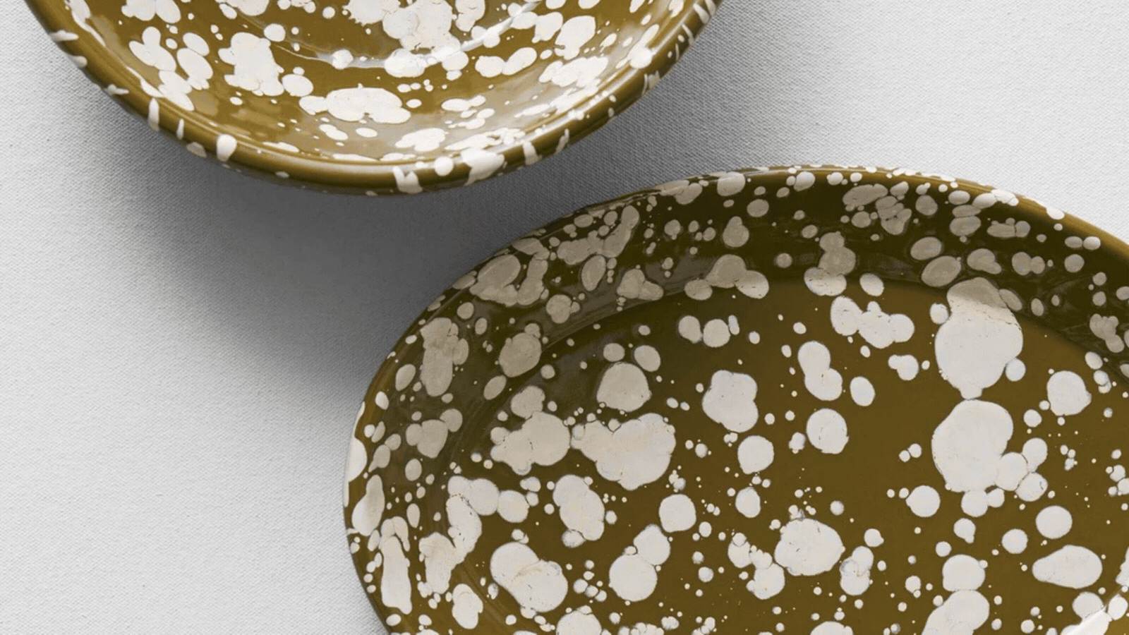 a gif of olive-colored enamelware with splattered print on it
