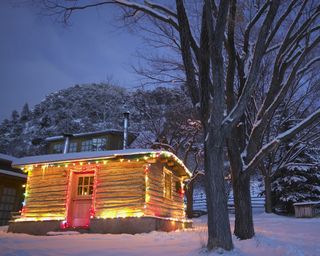 cabin in the snow lit up with christmas lights
