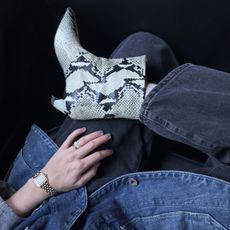 Snake skin print boots with black jeans and denim shirt and hand wearing gold watch and rings