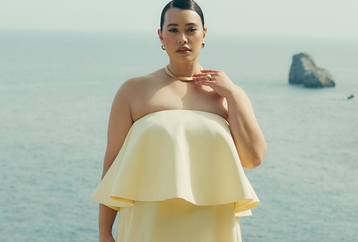 Model wears yellow plus-size wedding guest dress from Eloquii