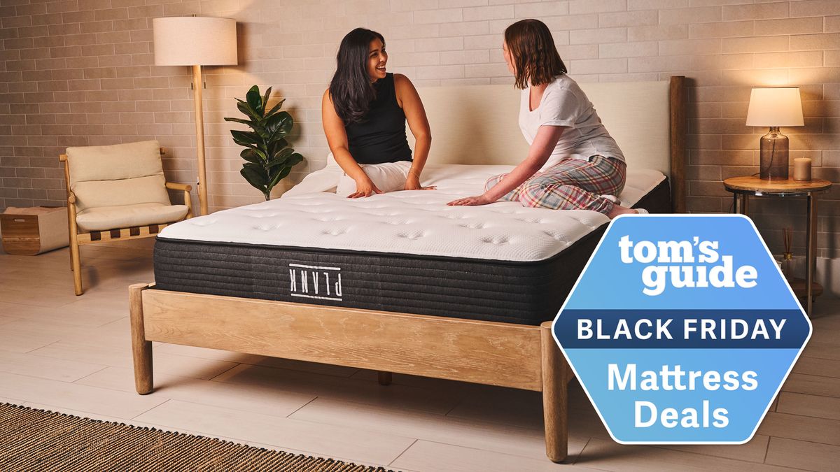 Two people sit on the Plank Firm mattress, feeling the ultra firm surface, a Tom&#039;s Guide Black Friday mattress deals graphic (right)