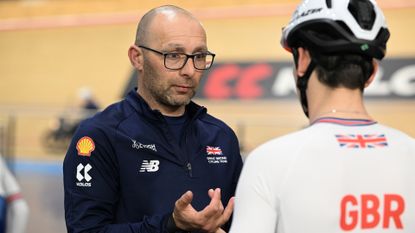 Stuart Blunt giving coaching advice to a Team GB rider inside Manchester Velodrome