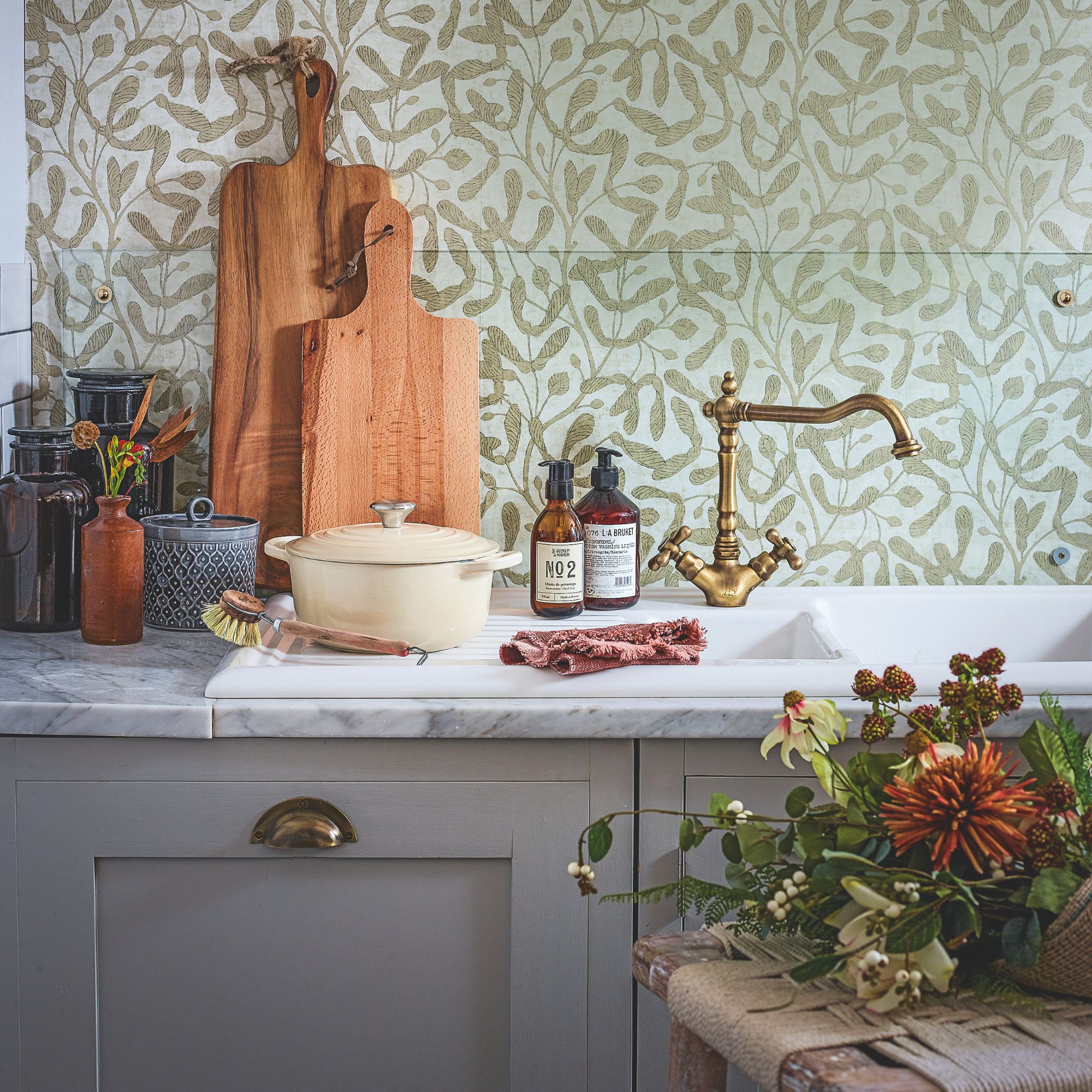 grey kitchen units against grey-green wallpaper