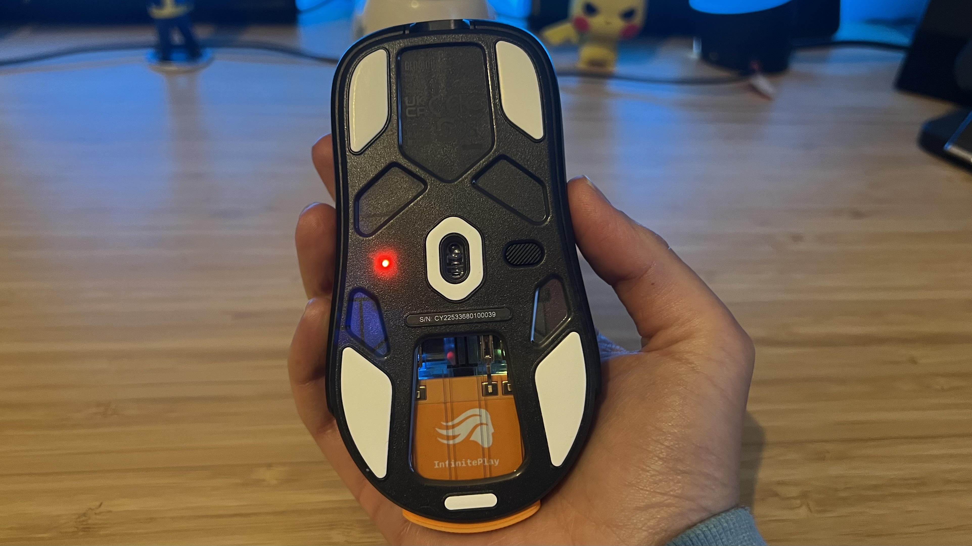 Hand holding Glorious Model O 3 Wireless upside down to show sensor and battery module